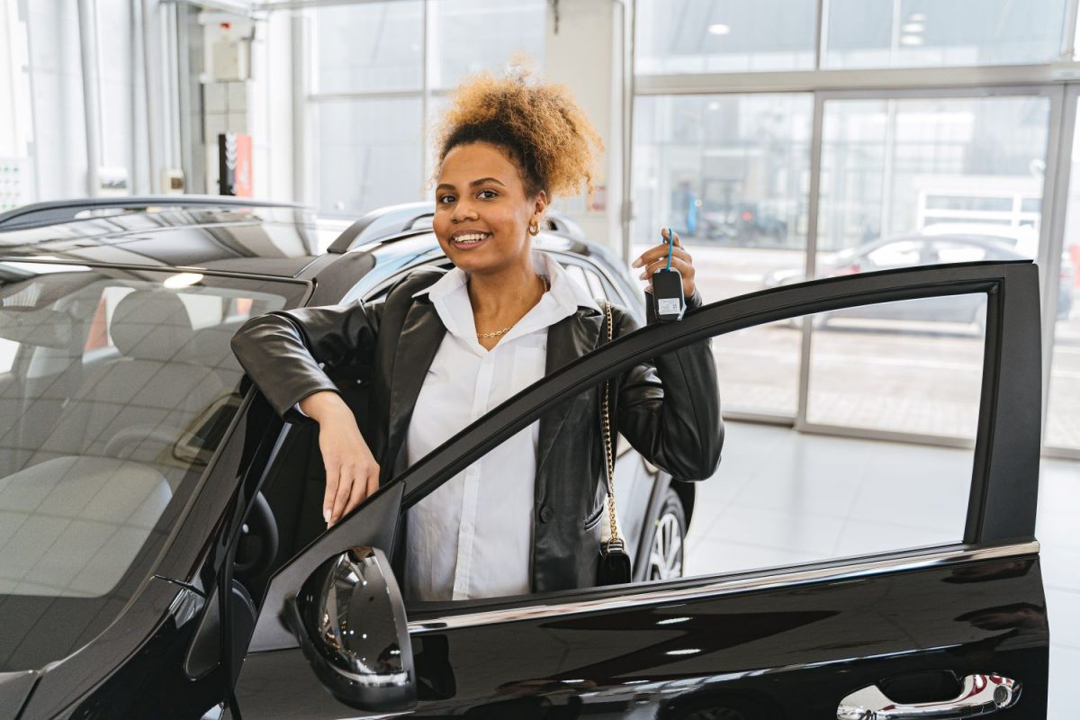 Mulher negra entre a porta de um carro segurando a chave, simulando como financiar carros usados