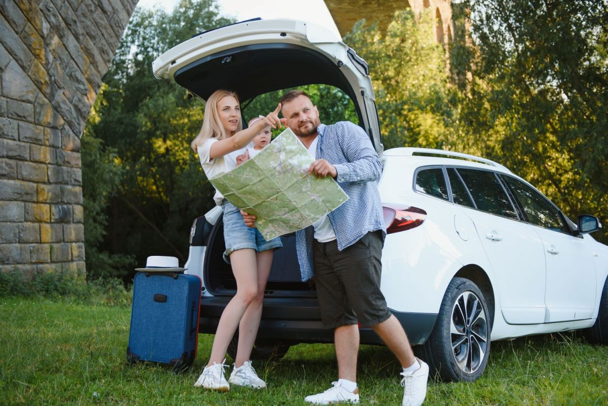 Família se preparando para viajar em frente a um carro com porta-malas grande