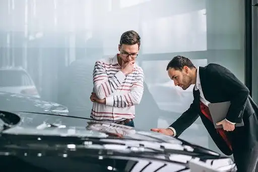 Dois homens analisam um carro em concessionária