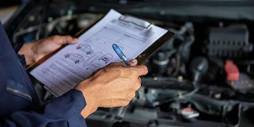 Técnico avaliando manutenção de veículo com planilha
