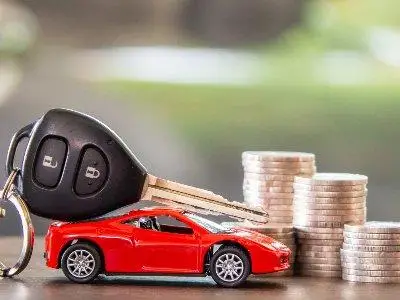 Chave de carro sobre modelinho e moedas empilhadas.